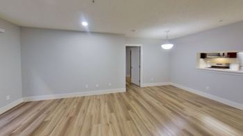 the living room and dining room of an empty house with wood flooring